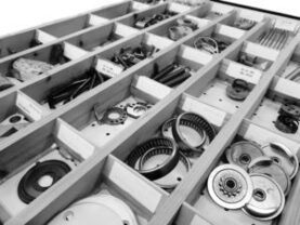 Boîte contenant différentes pièces de rechange pour machines à coudre industrielles.